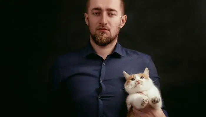 sombre looking man holding cat formally