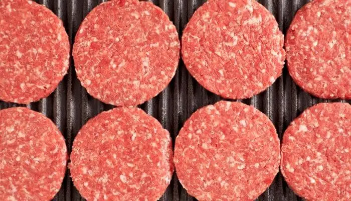 raw hamburgers on grill