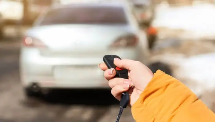 a hand activating a car alarm with the remote key